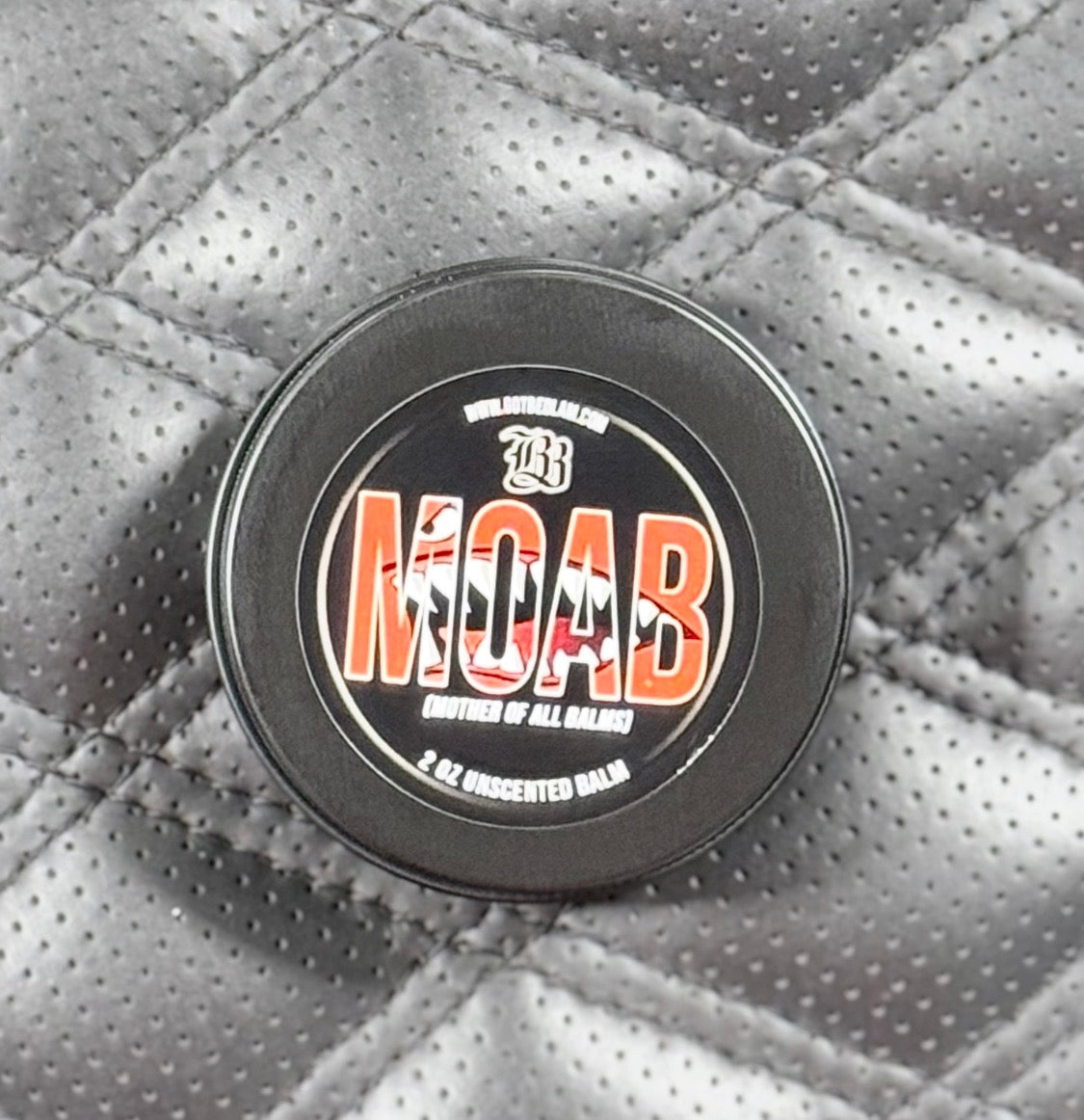 MOAB balm container on a textured gray surface