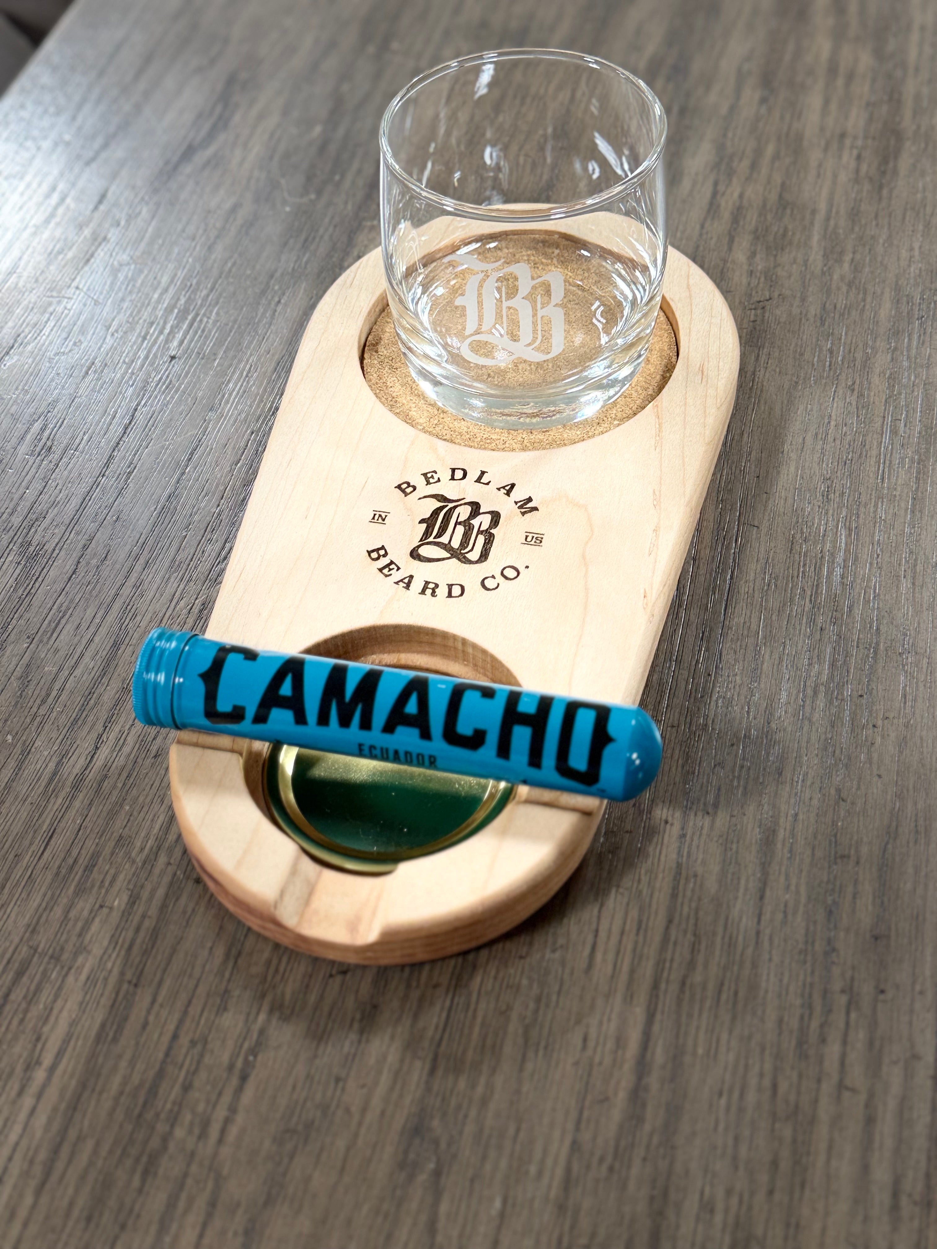 Wooden coaster with glass and bottle holder cork on a wooden surface, cigar holder, featuring Bedlam Beard Co branding.
