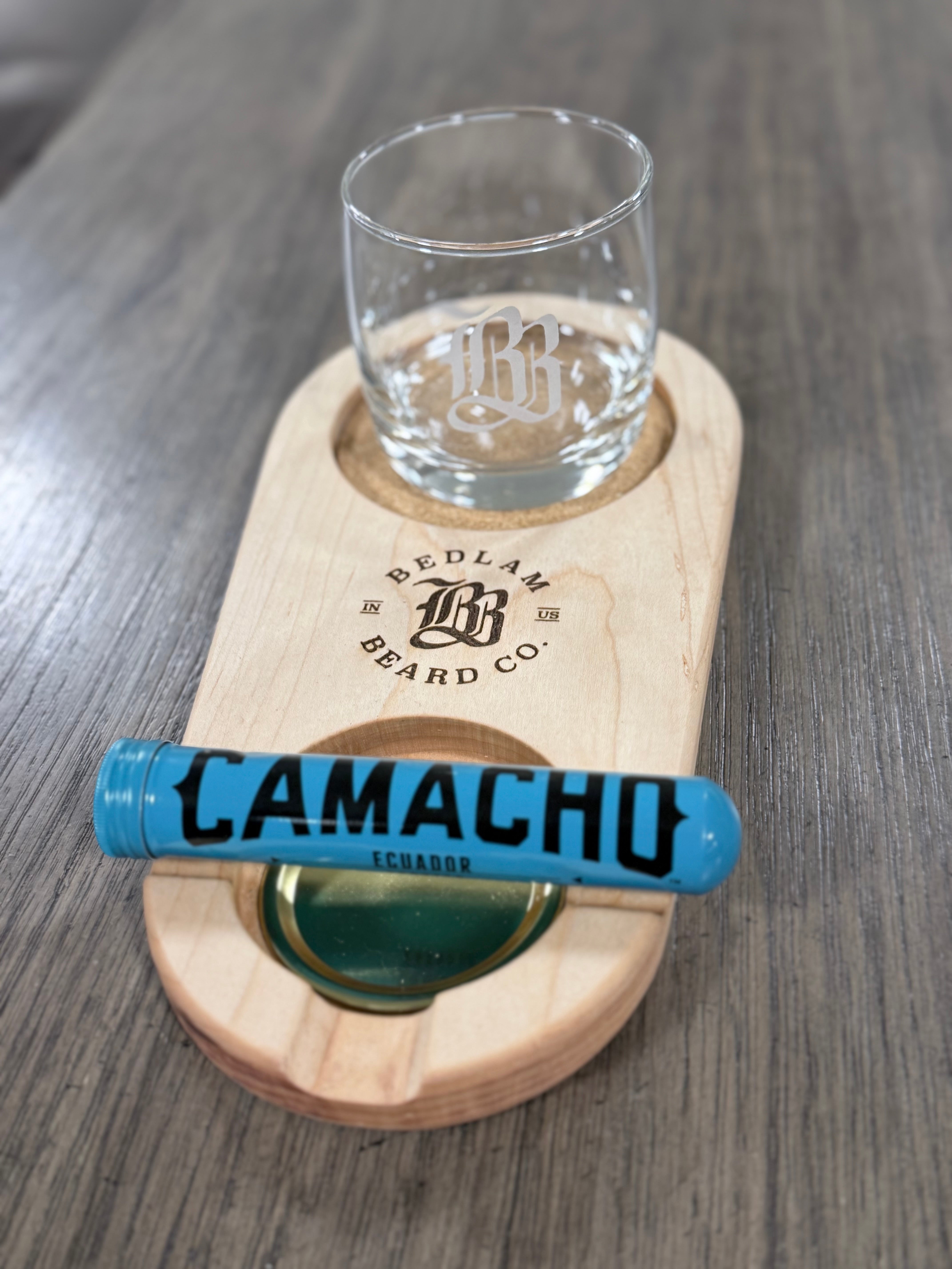 Wooden coaster with a glass of water and a Camacho cigar on a wooden surface