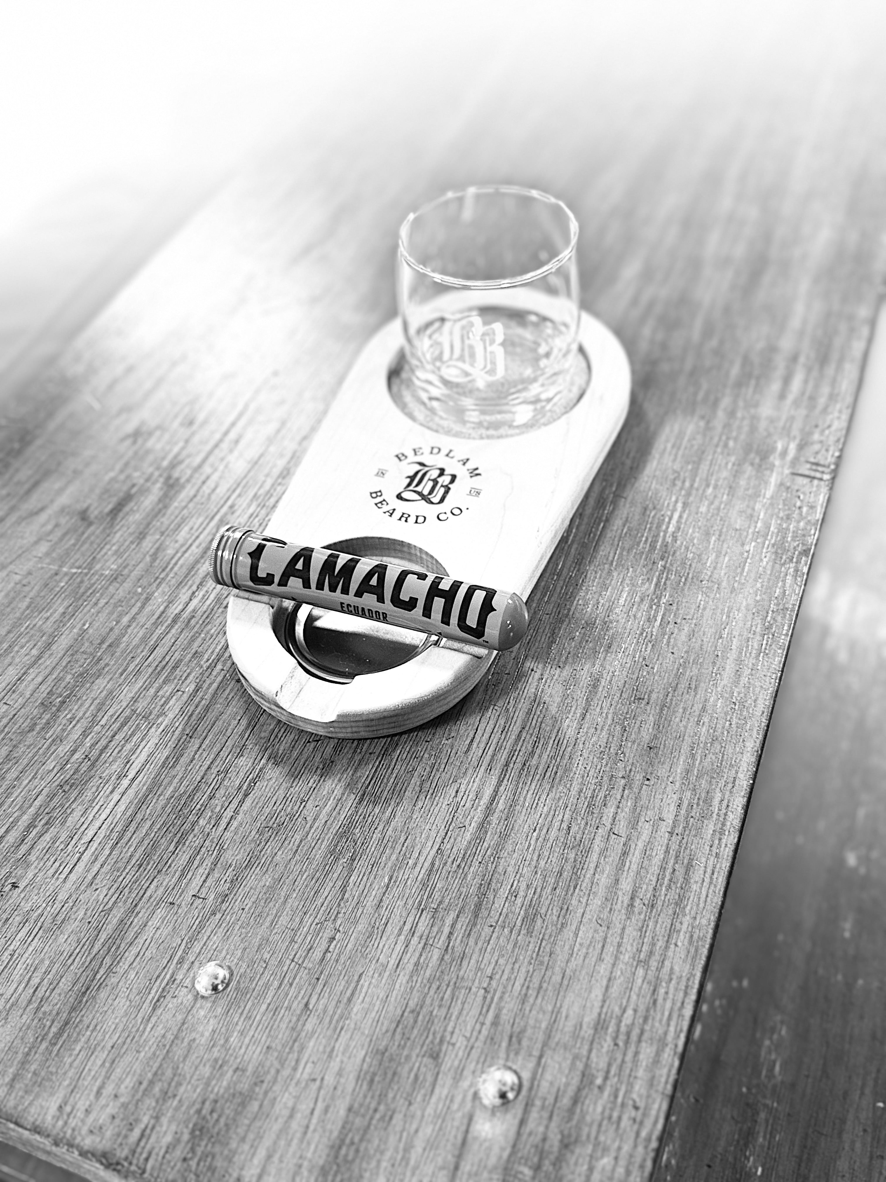 Wooden coaster with glass and bottle holder cork on a wooden surface, cigar holder, featuring Bedlam Beard Co branding.
